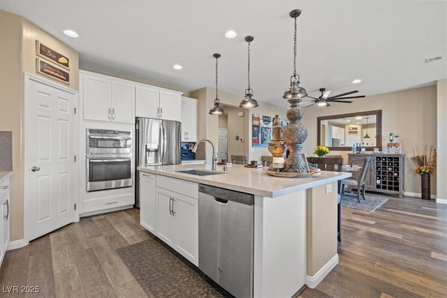 kitchen featuring white cabinets, appliances with stainless steel finishes, a sink, and wood finished floors