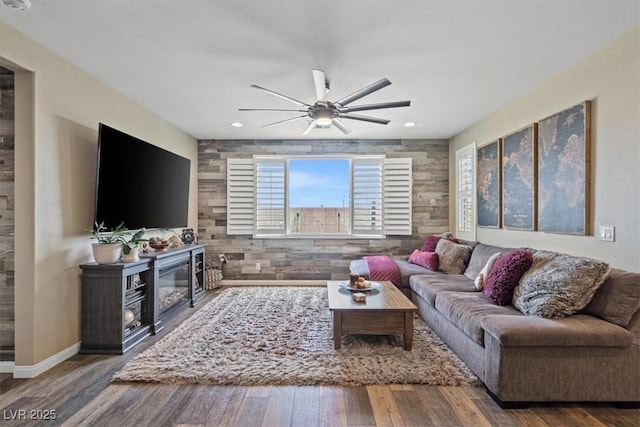 living area featuring a ceiling fan, a glass covered fireplace, wood finished floors, and recessed lighting