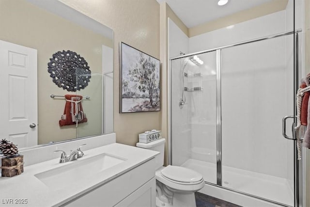 full bath featuring toilet, a shower stall, and vanity