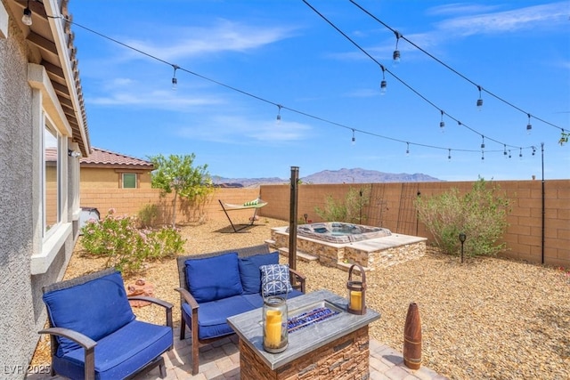 view of patio / terrace featuring a mountain view, a fenced backyard, and an outdoor living space with a fire pit