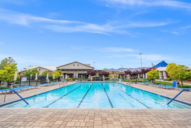 community pool featuring fence, a mountain view, and a patio
