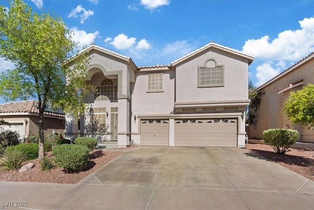 mediterranean / spanish house featuring a garage, stucco siding, a tile roof, and concrete driveway