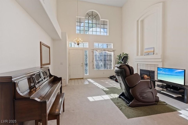 interior space featuring a high ceiling, a chandelier, a tiled fireplace, and carpet