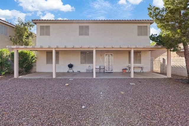 rear view of house with fence, stucco siding, and a patio area