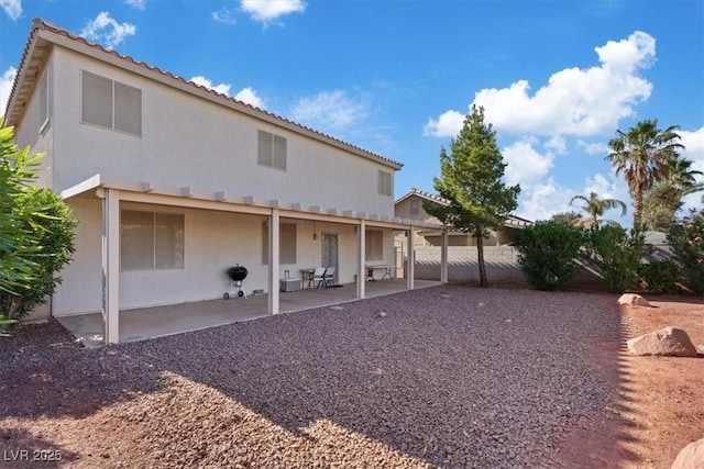 rear view of house featuring fence, stucco siding, and a patio area