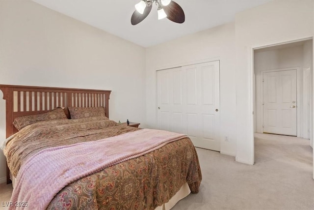 bedroom with baseboards, a ceiling fan, a closet, and light colored carpet