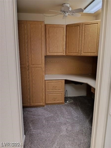 unfurnished office featuring carpet floors, ceiling fan, and built in study area