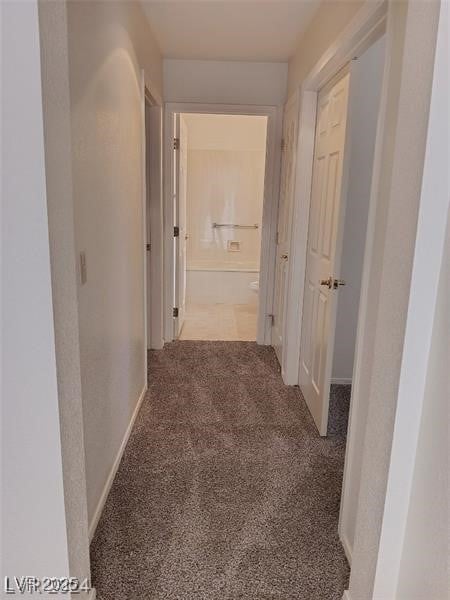corridor featuring baseboards and carpet