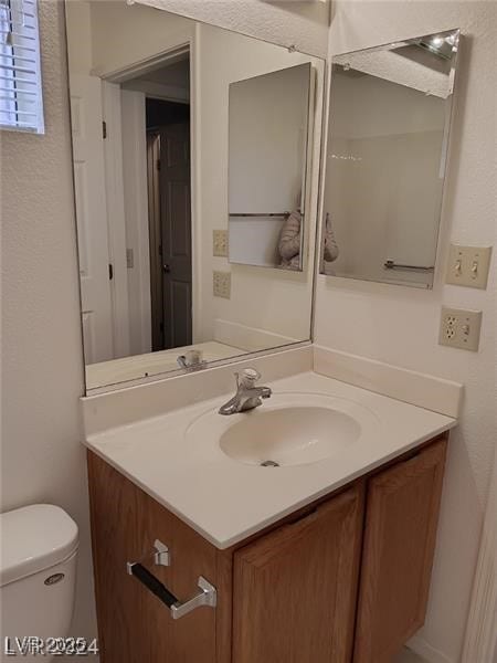 half bath featuring vanity and toilet