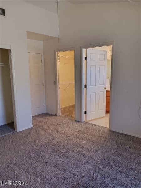 unfurnished bedroom with baseboards, visible vents, a closet, and light colored carpet