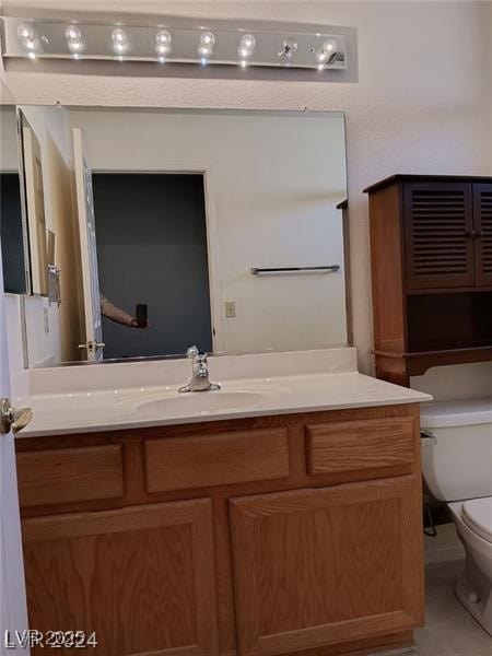 half bathroom featuring vanity, tile patterned floors, and toilet