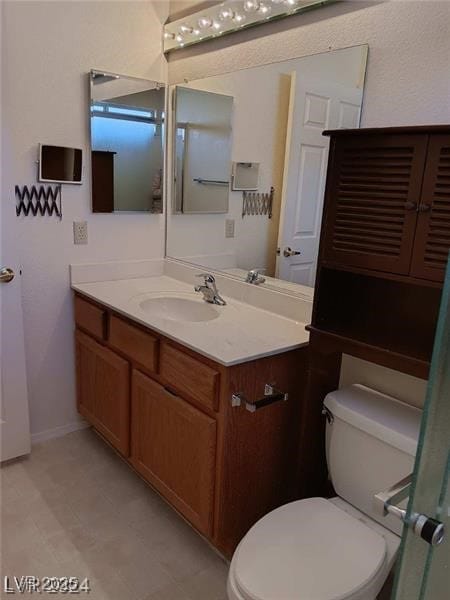 bathroom featuring vanity, baseboards, tile patterned floors, and toilet
