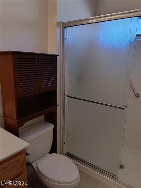 bathroom featuring toilet, tile patterned floors, a shower stall, and vanity