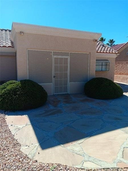 property entrance with a tile roof and stucco siding