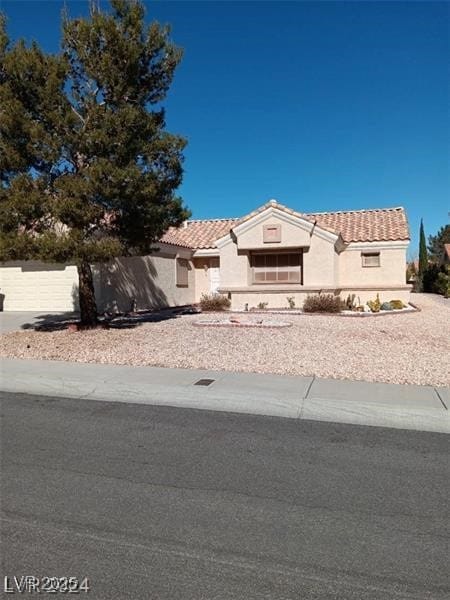 view of front of home featuring stucco siding, a tiled roof, and fence