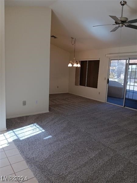 carpeted spare room featuring visible vents, baseboards, lofted ceiling, and ceiling fan with notable chandelier