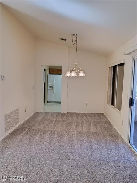 empty room featuring visible vents, light carpet, and an inviting chandelier