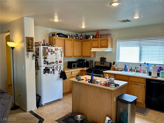 kitchen featuring freestanding refrigerator, black dishwasher, under cabinet range hood, a sink, and gas stove