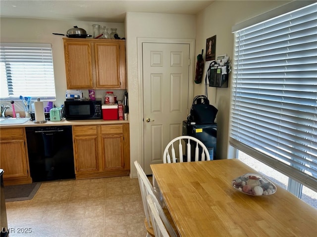 kitchen with light countertops, black appliances, a sink, and a healthy amount of sunlight