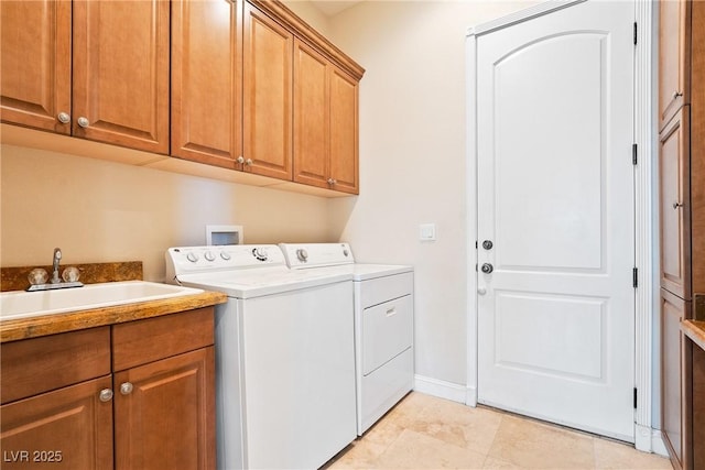 laundry area featuring baseboards, a sink, cabinet space, and independent washer and dryer