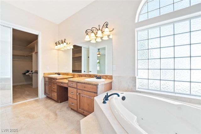 bathroom featuring a jetted tub, double vanity, a sink, and a walk in closet