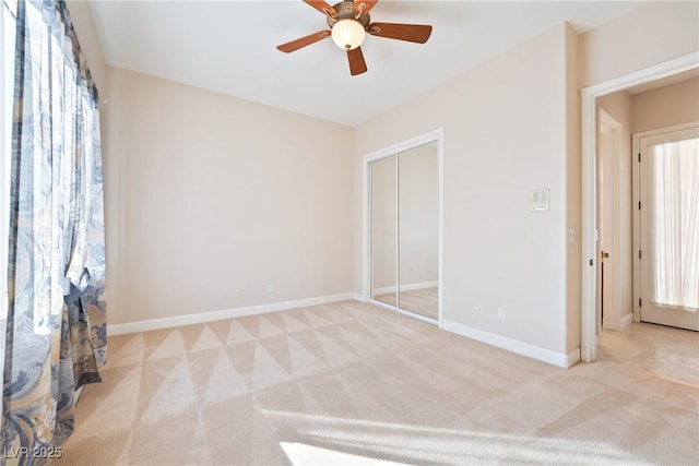 unfurnished bedroom featuring a ceiling fan, baseboards, light carpet, and a closet