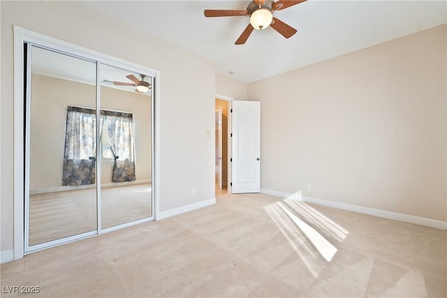 unfurnished bedroom featuring baseboards, a ceiling fan, a closet, and light colored carpet