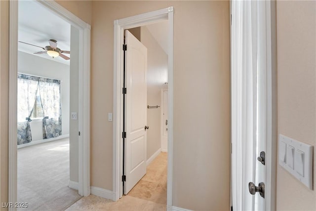 hallway with baseboards and light carpet
