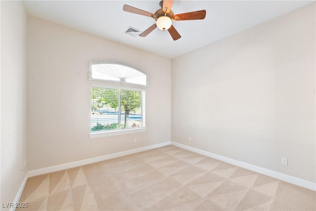 spare room featuring light colored carpet, a ceiling fan, baseboards, and visible vents