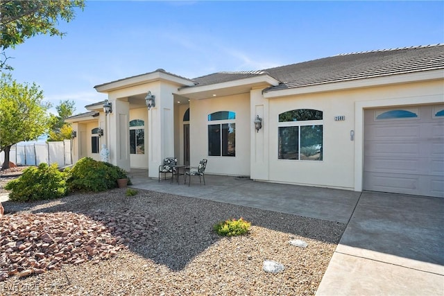 exterior space with stucco siding, an attached garage, and a tile roof