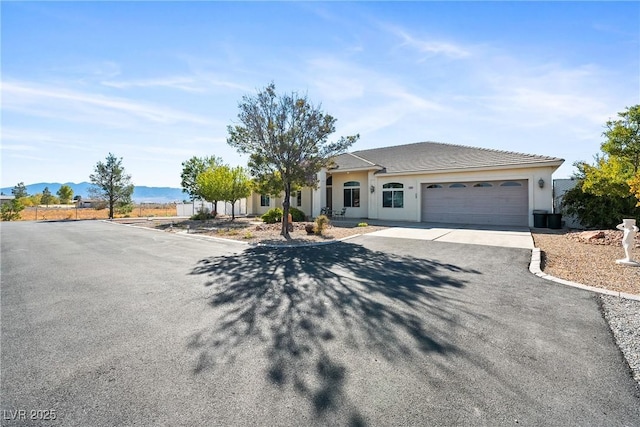 ranch-style house featuring a mountain view, an attached garage, driveway, and stucco siding