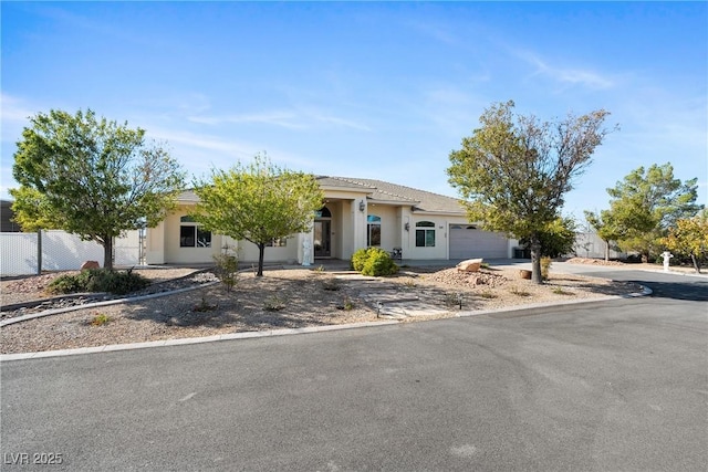 view of front of home with a garage, fence, stucco siding, and driveway