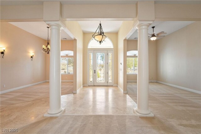 carpeted entryway featuring baseboards, a ceiling fan, and ornate columns