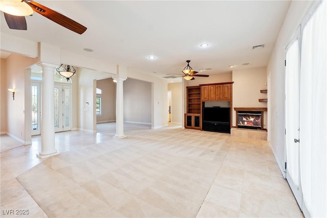 unfurnished living room with ceiling fan, a glass covered fireplace, recessed lighting, baseboards, and decorative columns
