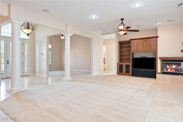 unfurnished living room featuring a ceiling fan, decorative columns, a wealth of natural light, and visible vents