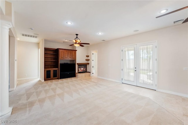 unfurnished living room featuring light colored carpet, ceiling fan, a glass covered fireplace, and baseboards