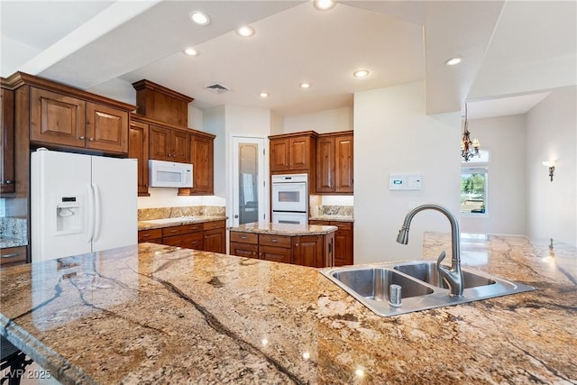 kitchen featuring visible vents, white appliances, recessed lighting, a center island, and a sink