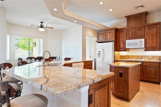 kitchen with ceiling fan, visible vents, a spacious island, a sink, and white appliances