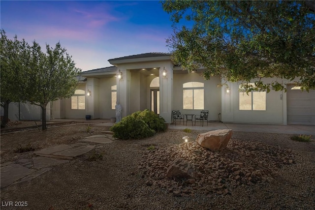 view of front facade featuring a patio, a tile roof, and stucco siding