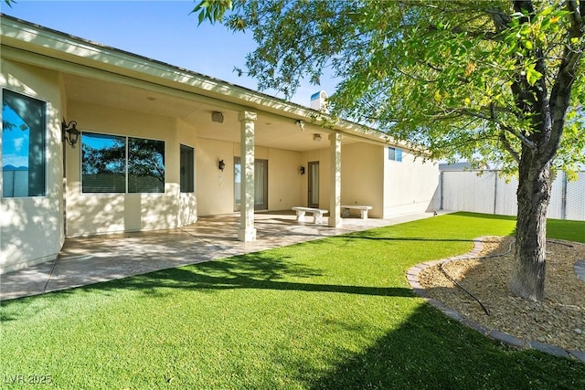 rear view of property with a lawn, a patio, fence, and stucco siding