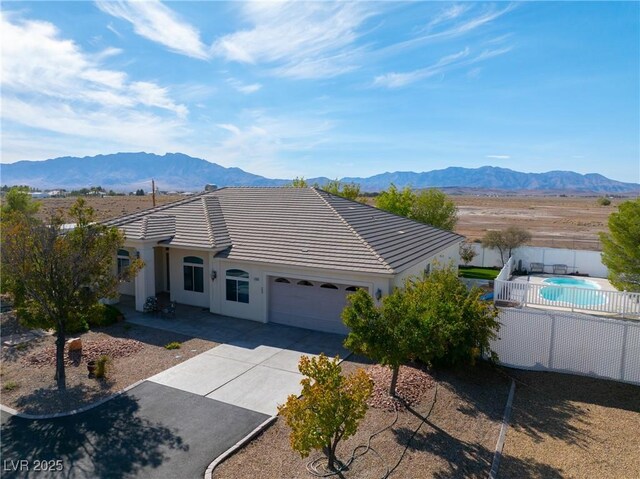 exterior space with a tiled roof, an attached garage, fence, and a mountain view