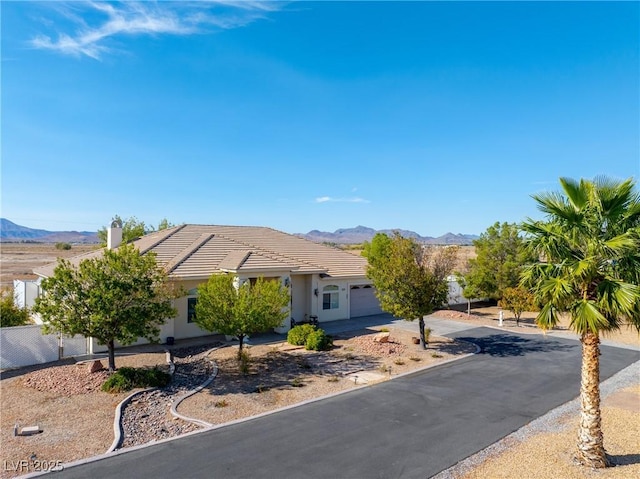 view of front of property with a tile roof, a mountain view, concrete driveway, an attached garage, and stucco siding