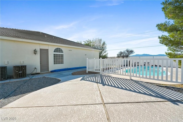 view of patio with a fenced in pool, fence, and central air condition unit
