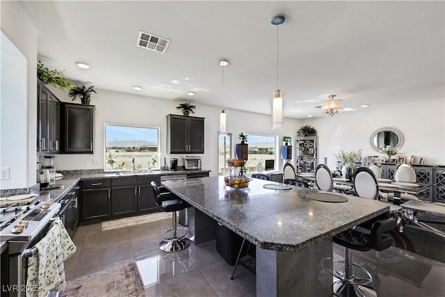 9045 Knots Estate St, Las Vegas, NV 89139 - kitchen with stainless steel range with gas cooktop, visible vents, a breakfast bar, and dark stone counters