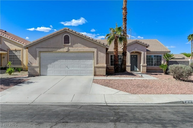 mediterranean / spanish-style home with concrete driveway, stucco siding, an attached garage, and a tiled roof