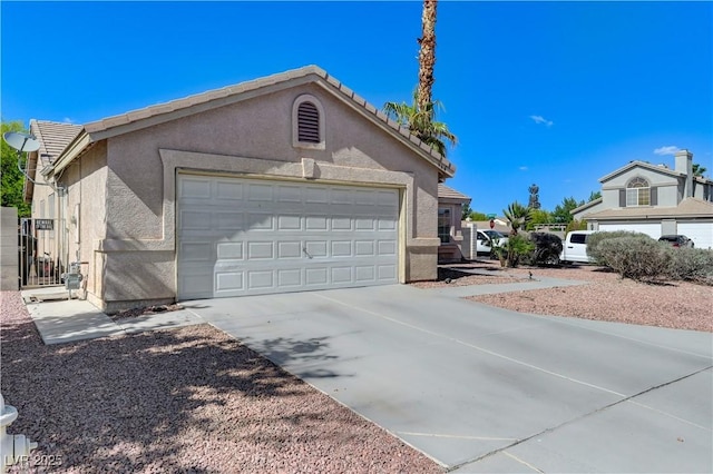 view of property exterior with a garage, stucco siding, driveway, and a tile roof