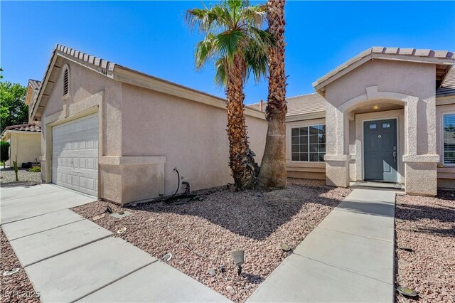 view of front of house featuring stucco siding, an attached garage, and driveway