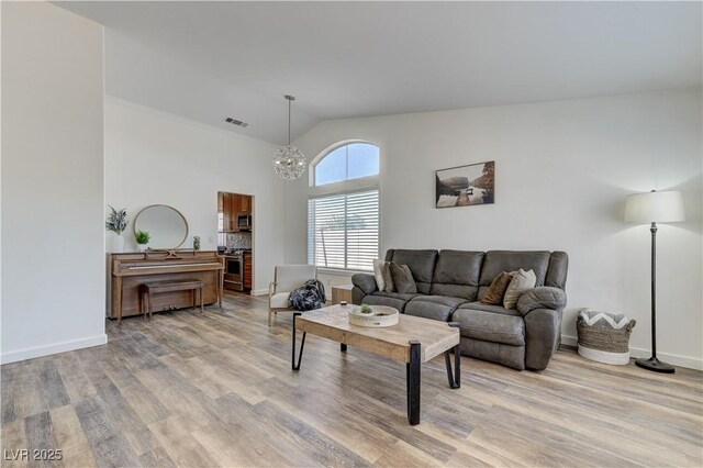 living area featuring visible vents, vaulted ceiling, baseboards, a notable chandelier, and light wood-style flooring