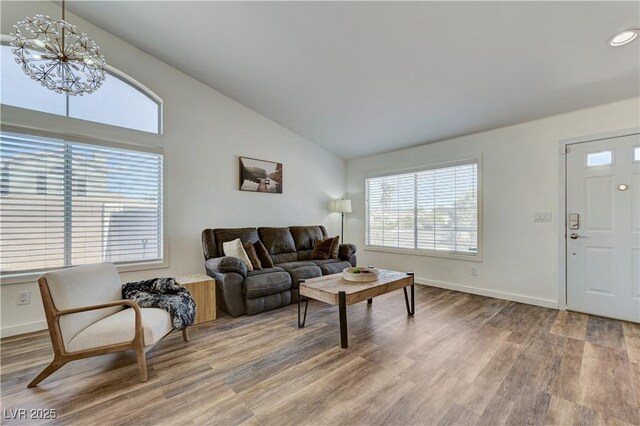 living room with a notable chandelier, high vaulted ceiling, recessed lighting, baseboards, and wood finished floors