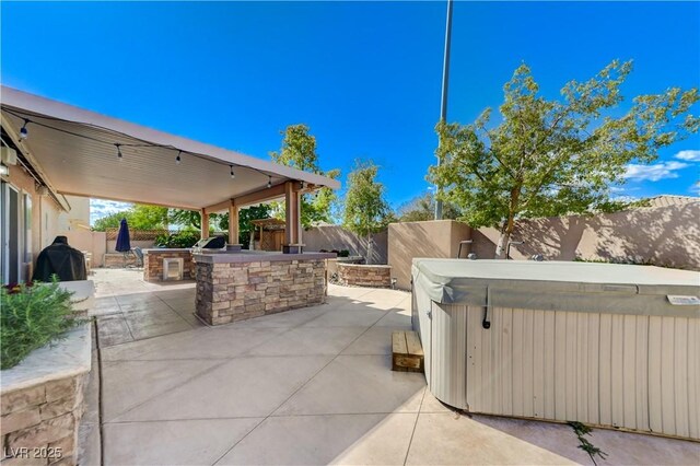 view of patio featuring a fenced backyard, outdoor dry bar, and a hot tub